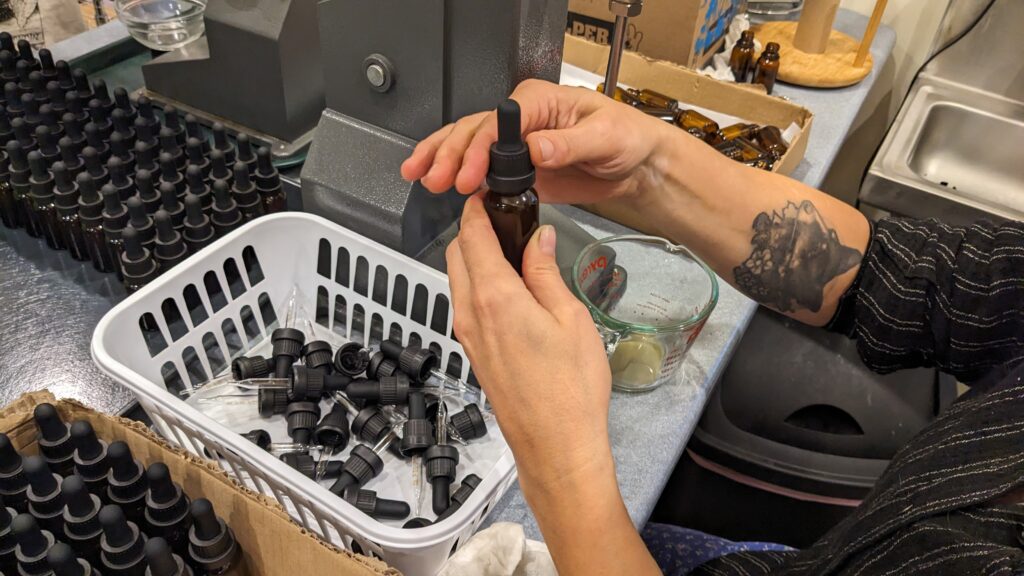 Hands twisting the caps on tinctures near a bottle filling machine